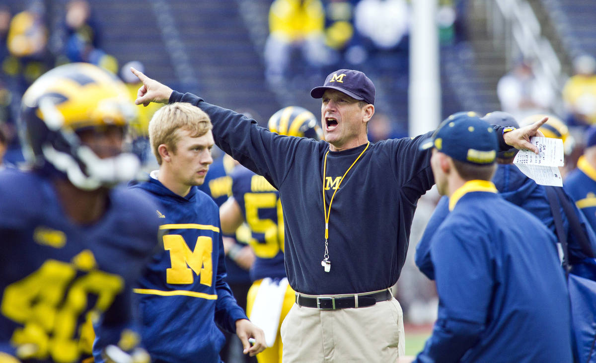 Michigan head coach Jim Harbaugh directs his players during warmups before an NCAA college foot ...