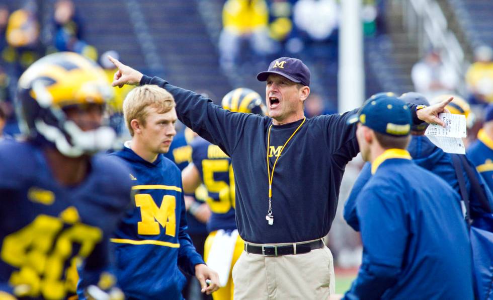Michigan head coach Jim Harbaugh directs his players during warmups before an NCAA college foot ...