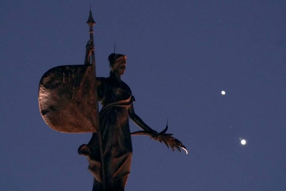 A statue atop a half-scale replica of Seville, Spain's La Giralda Tower stands in the foregroun ...