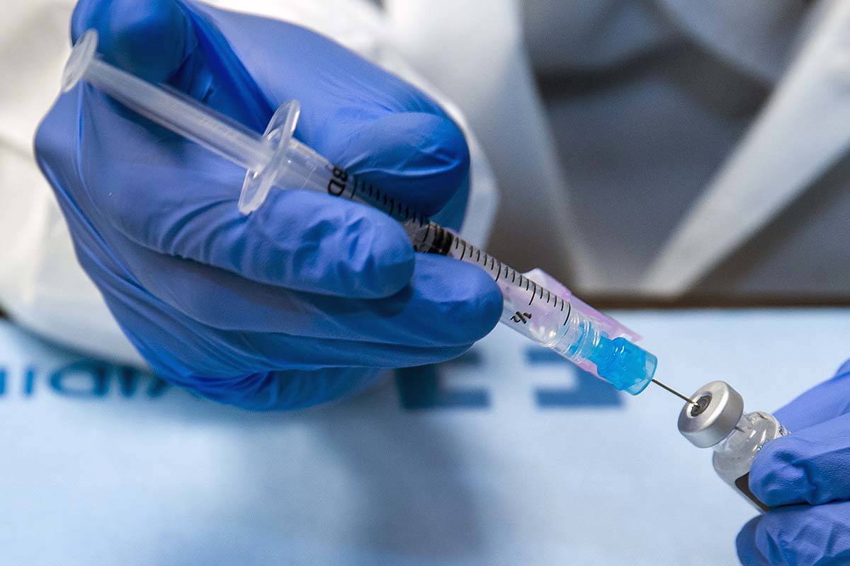 Student pharmacist Wilbur Quimba loads up new syringes with vaccine as University Medical Cente ...