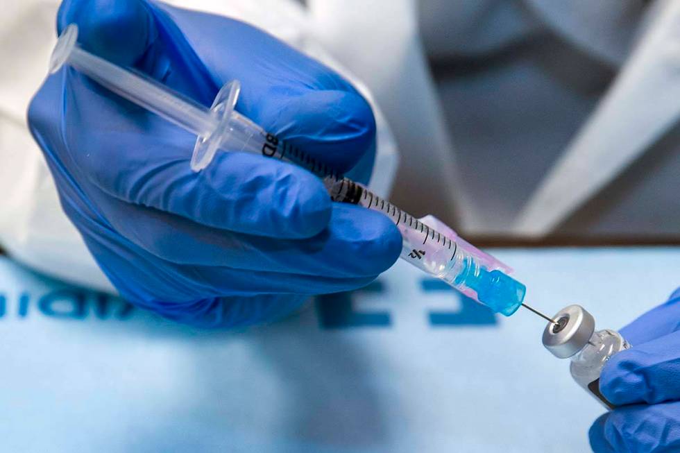 Student pharmacist Wilbur Quimba loads up new syringes with vaccine as University Medical Cente ...