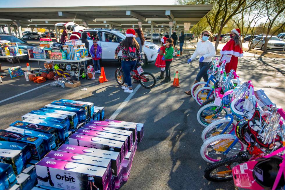 Volunteers hurry about delivering gifts during the first NLVPD Holiday Toy Giveaway drive-thru ...