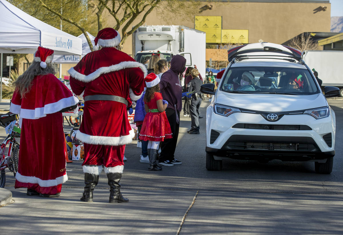 Santa and Mrs. Claus greet drivers during the first NLVPD Holiday Toy Giveaway drive-thru event ...