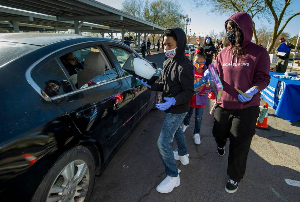 Jaeion Severin, 12, left, delivers gifts with Nyiah Warren, 7, center, and Tricia Turner during ...