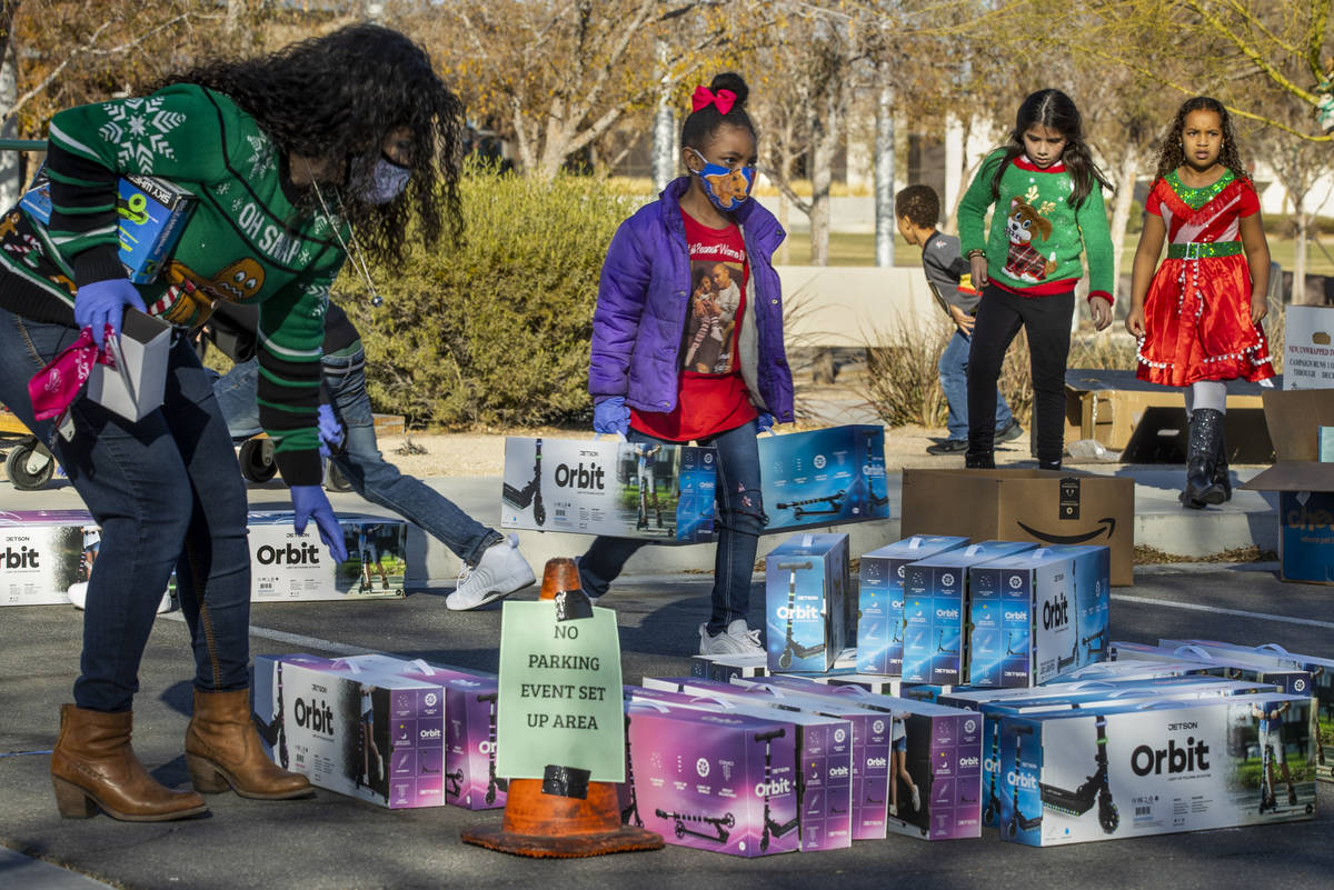 Nyiah Warren, 7, center, stacks up scooters during the first NLVPD Holiday Toy Giveaway drive-t ...