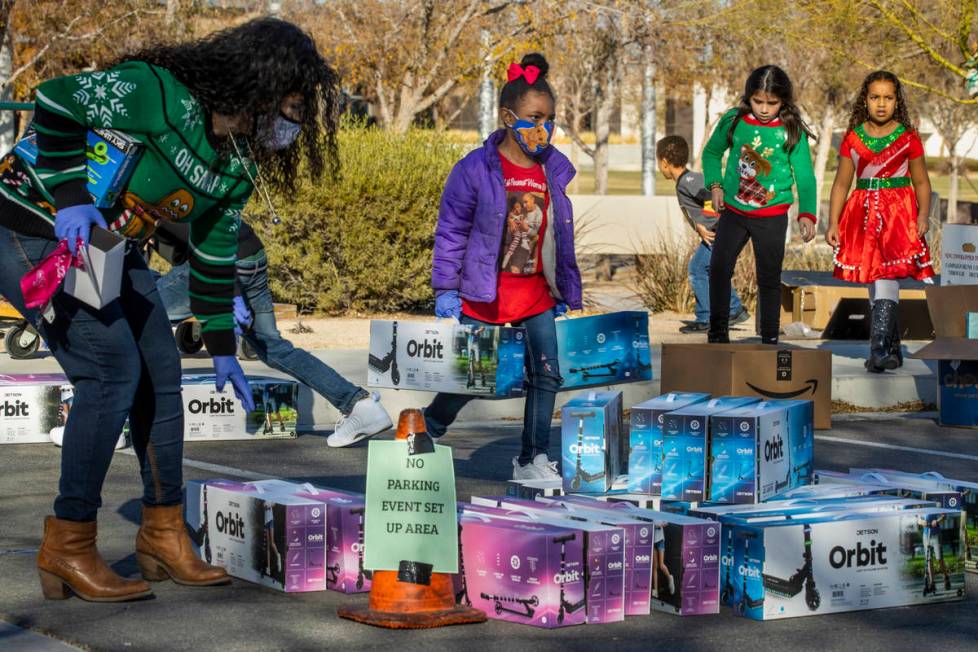 Nyiah Warren, 7, center, stacks up scooters during the first NLVPD Holiday Toy Giveaway drive-t ...