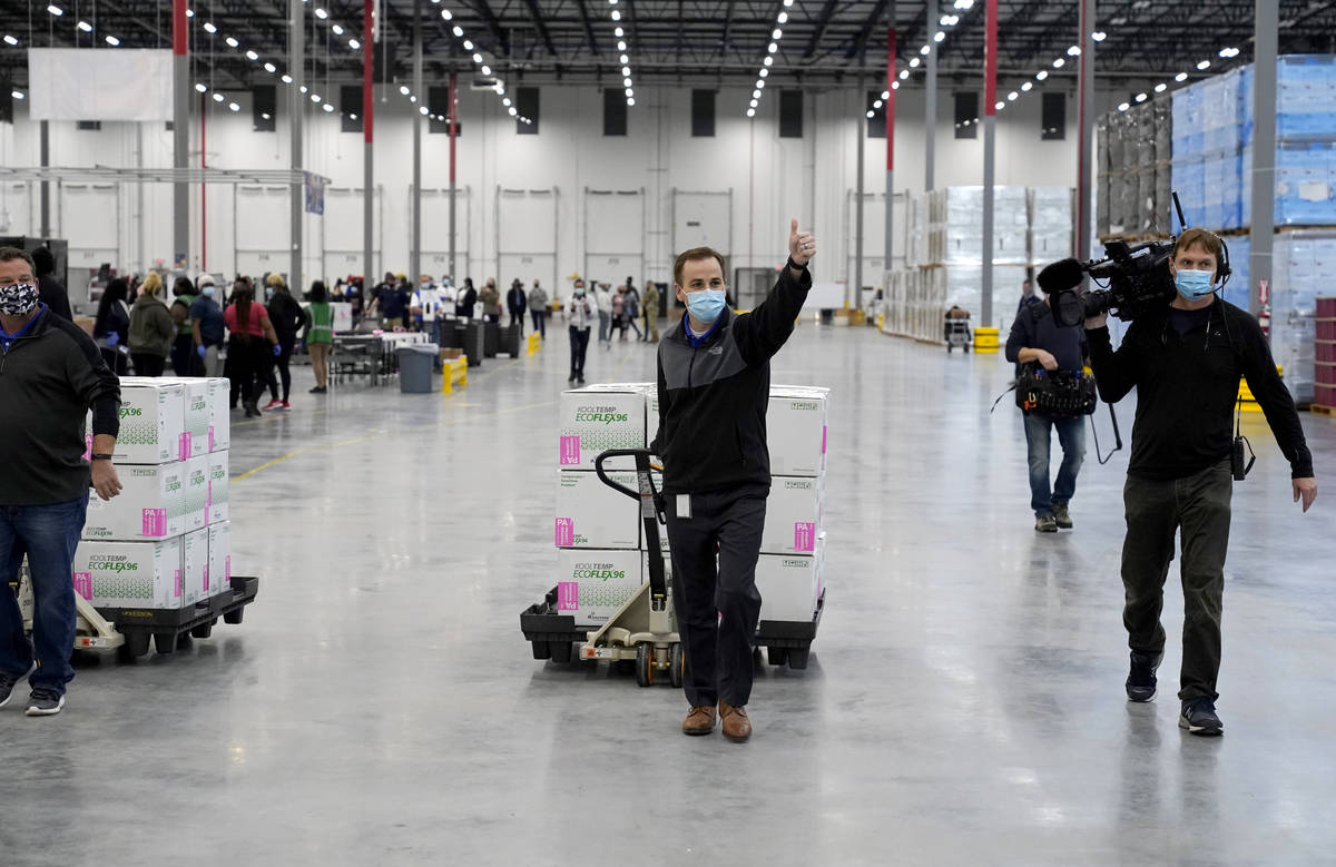 A worker gives a thumbs up while transporting boxes containing the Moderna COVID-19 vaccine to ...