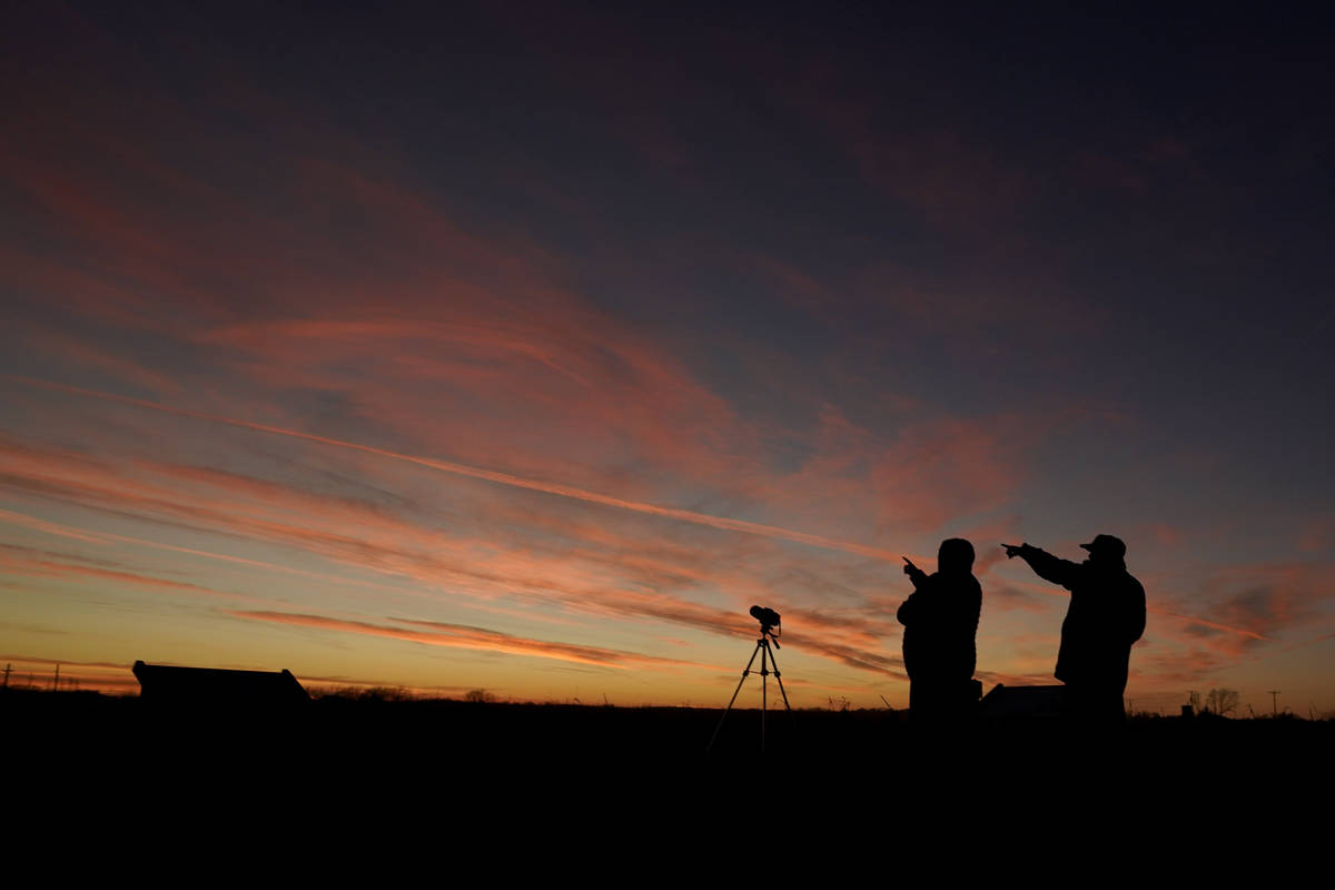 People are silhouetted against the sky at dusk as they watch the alignment of Saturn and Jupite ...