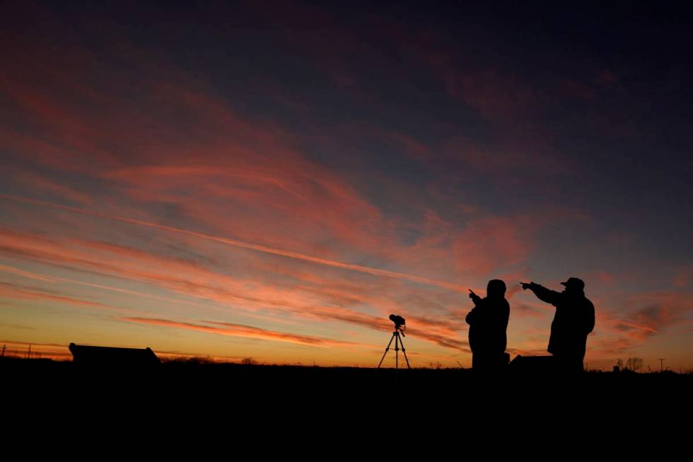 People are silhouetted against the sky at dusk as they watch the alignment of Saturn and Jupite ...