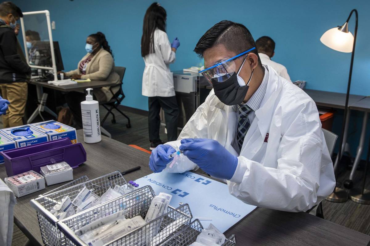 Student pharmacist Wilbur Quimba loads up new syringes with vaccine as University Medical Cente ...