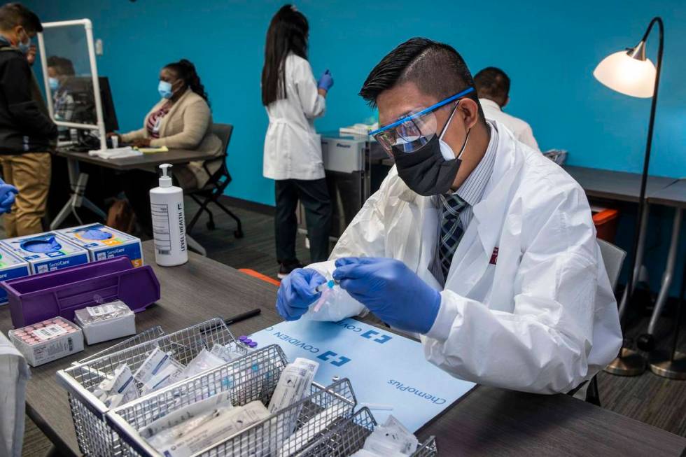 Student pharmacist Wilbur Quimba loads up new syringes with vaccine as University Medical Cente ...