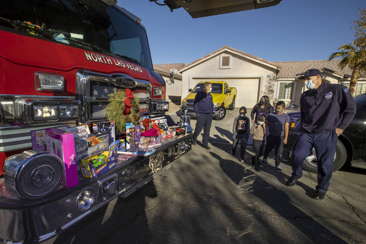 North Las Vegas Fire Truck 52 crew member Brandon Parry, right, welcomes over Laura Alicea, cen ...