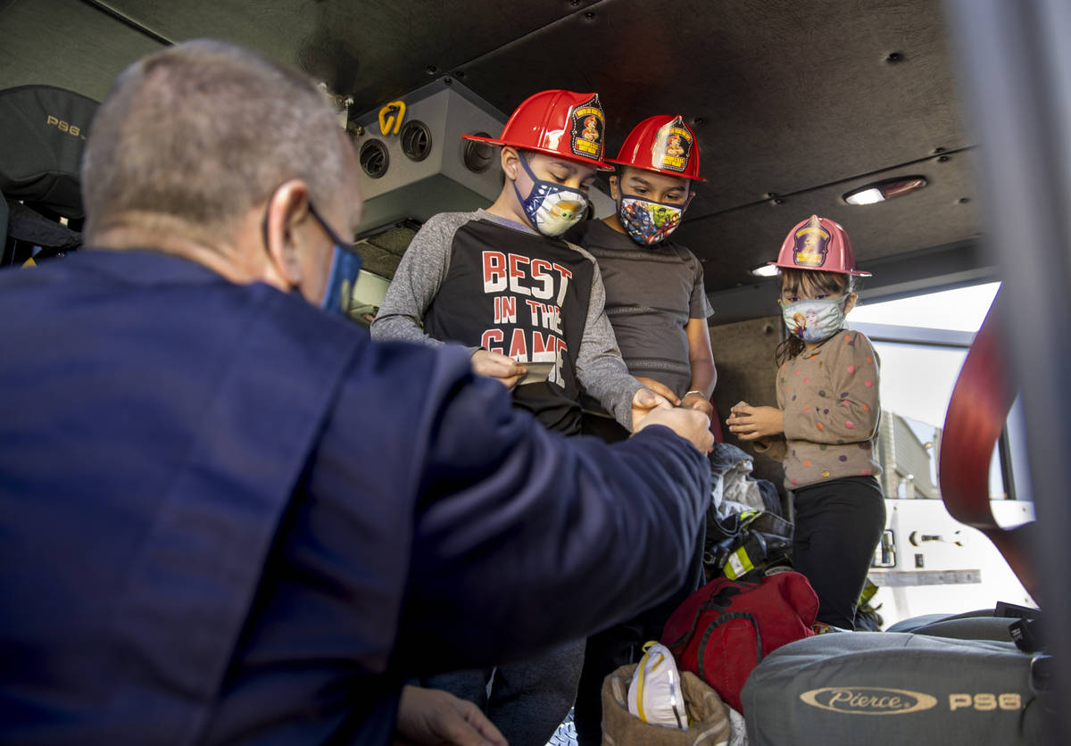(From left) North Las Vegas Fire Truck 52 crew member Reese Williams passes out hats and badges ...