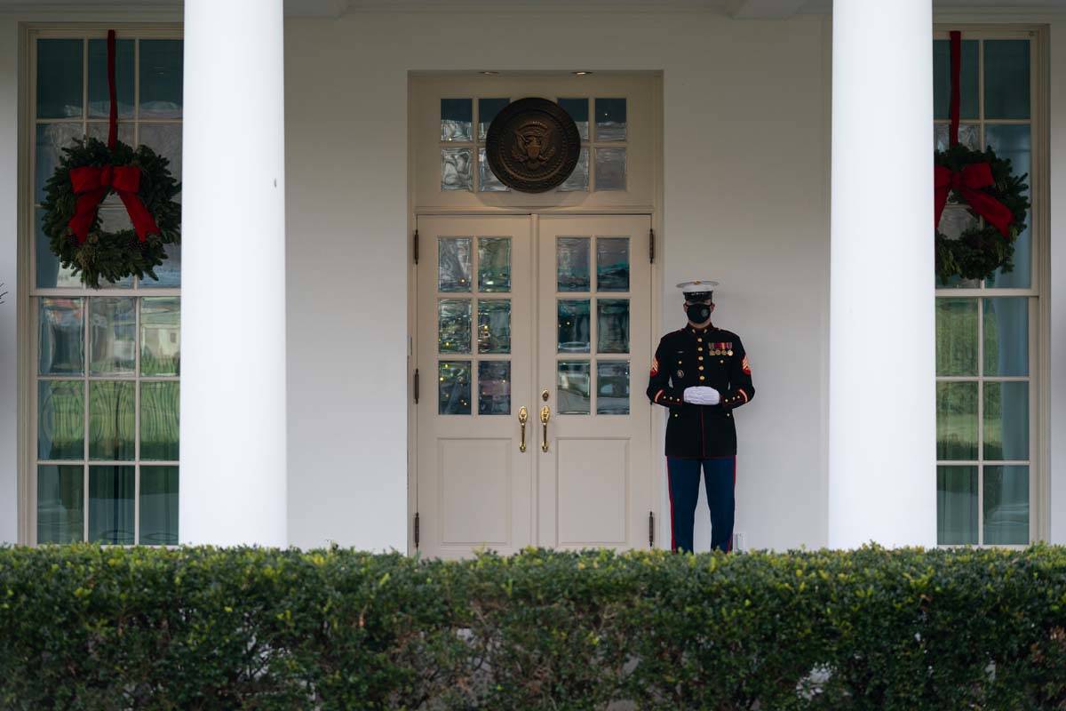 A Marine stands outside the entrance to the West Wing of the White House, signifying the Presid ...