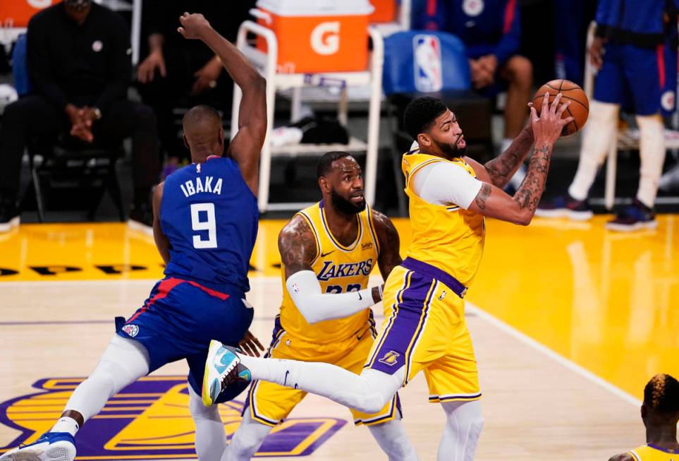 Los Angeles Lakers forward Anthony Davis, right, grabs a rebound next to teammate LeBron James, ...