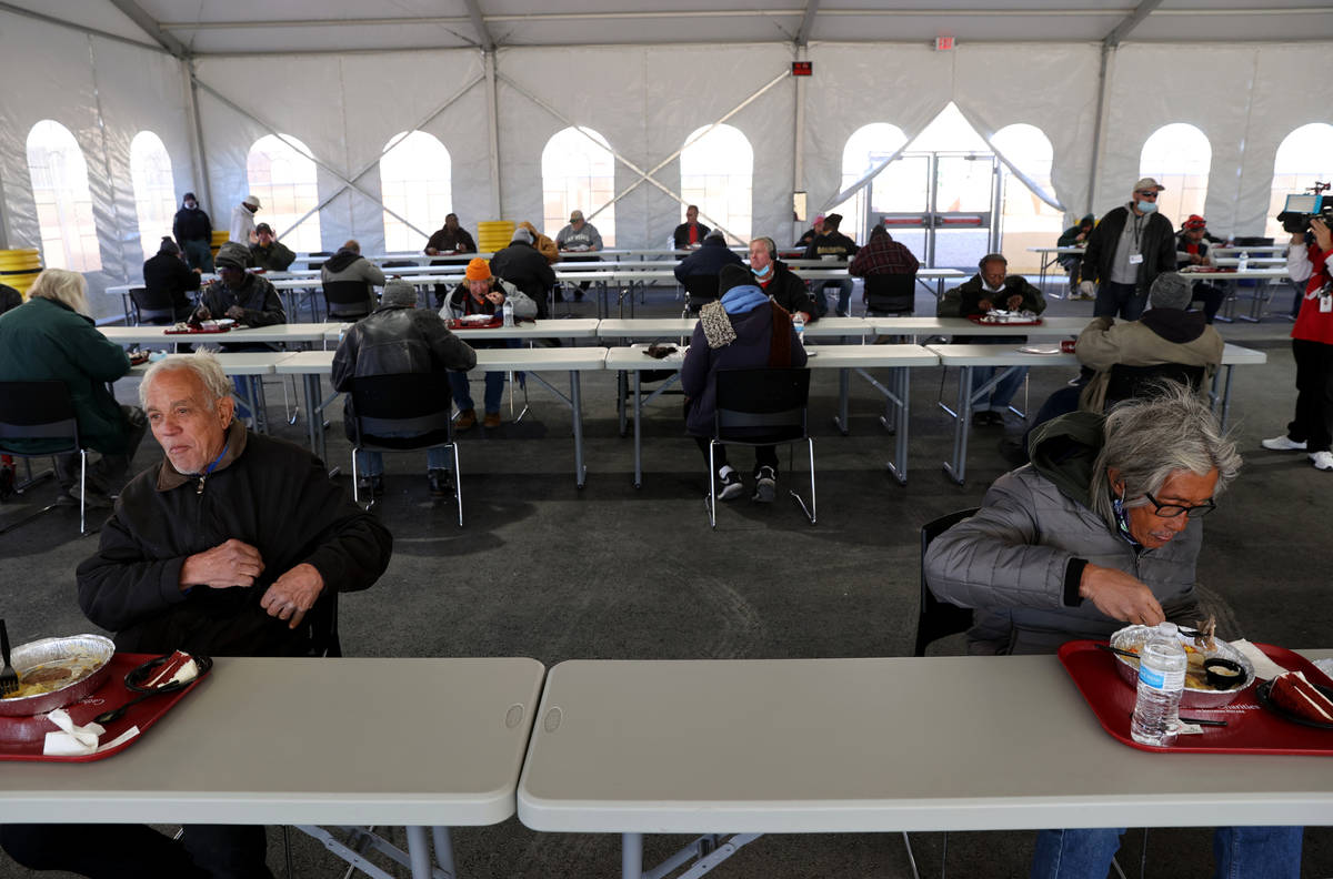 People, including James T. Kirk, 68, left, and Gerardo Eugenio, 72, eat a Christmas meal of pri ...