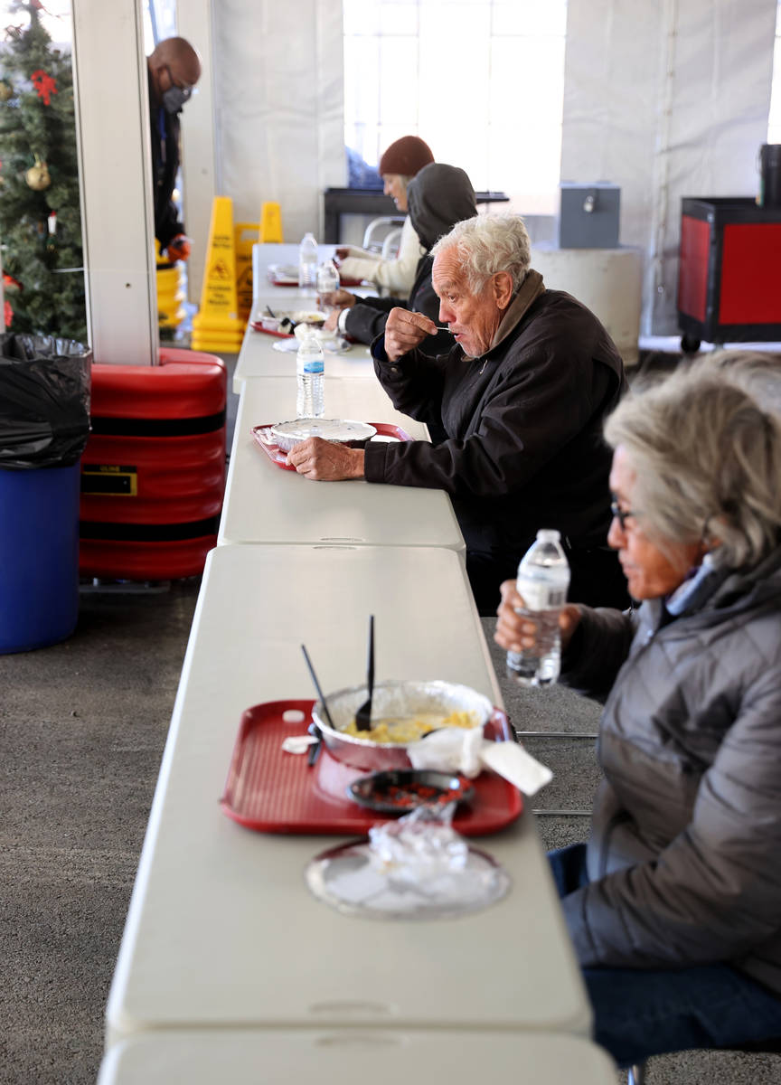 People, including James T. Kirk, 68, left, and Gerardo Eugenio, 72, eat a Christmas meal of pri ...