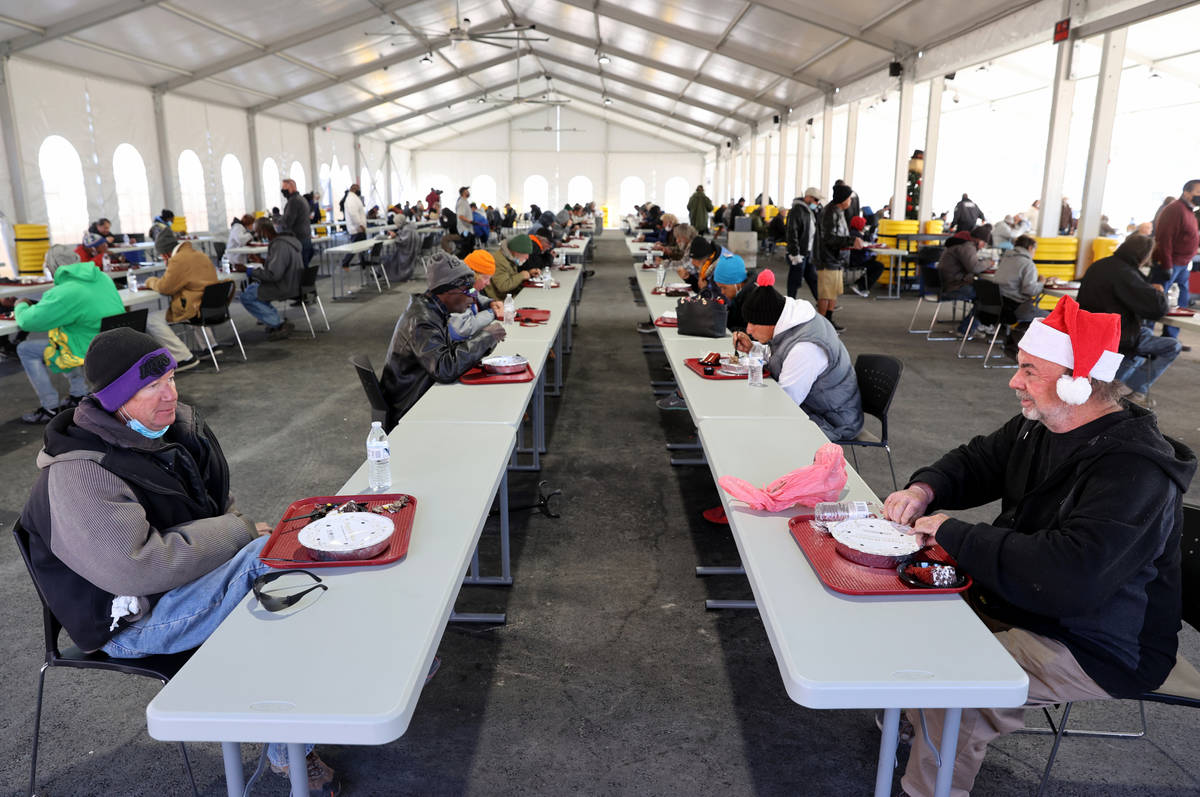 People, including Sean Hart, 58, left, and Gregory Lowery, 60, eat a Christmas meal of prime ri ...