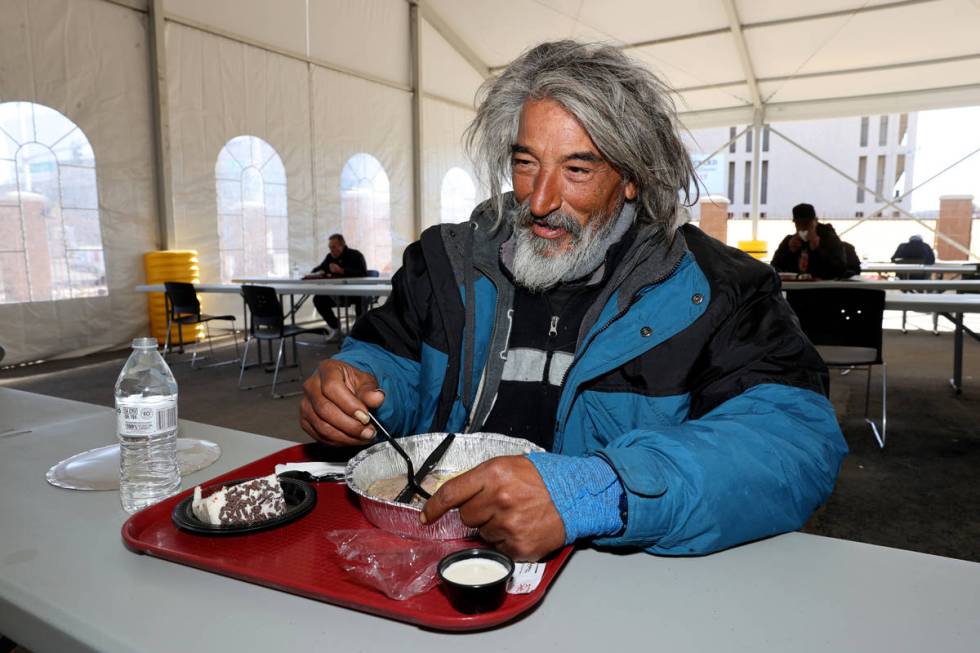 People, including Edward Bernal eat a Christmas meal of prime rib with horseradish cream sauce, ...