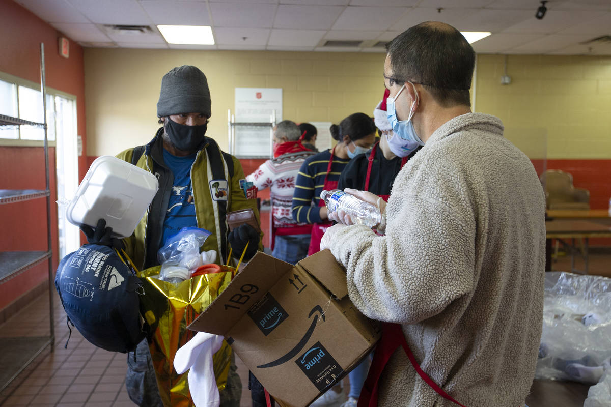 Salvador Hernandez, left, accepts water and socks from volunteer Mike Serenco during a free Chr ...