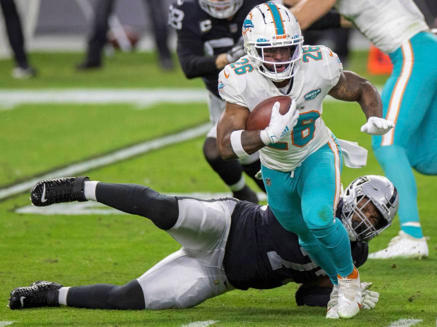 Miami Dolphins running back Salvon Ahmed (26) breaks the tackle of Raiders defensive tackle Mau ...