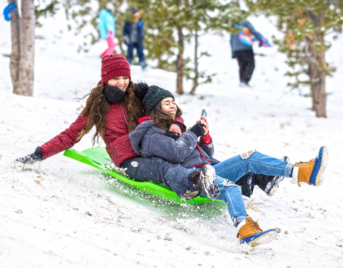 America Reinozo, left, and Valeria Casta–eda sled down a hill at Lee Canyon on Monday, D ...