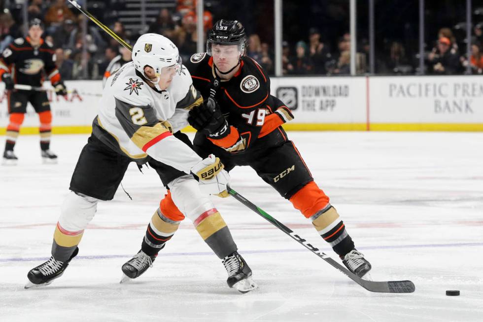 Vegas Golden Knights defenseman Zach Whitecloud, left, passes around Anaheim Ducks left wing Ma ...