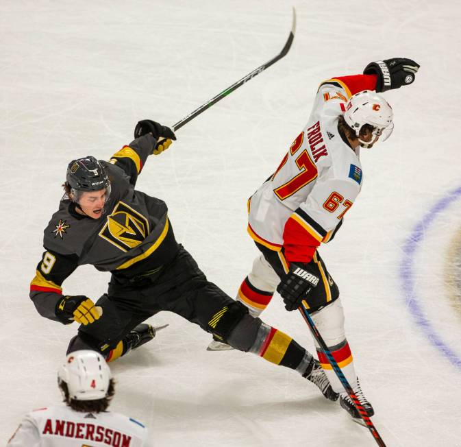 Vegas Golden Knights center Cody Glass (9, left) is takes dow by Calgary Flames right wing Mich ...