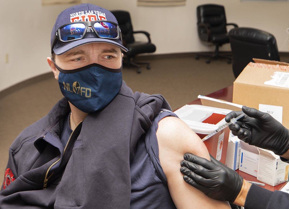 North Las Vegas Fire Department Capt. David Carraway, 36, left, gets a COVID-19 vaccine from em ...