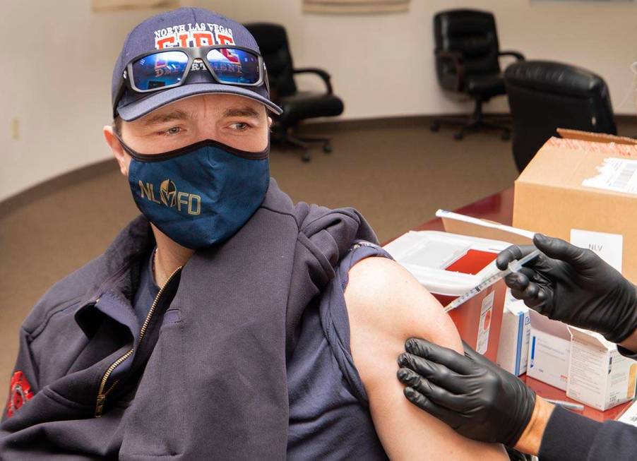 North Las Vegas Fire Department Capt. David Carraway, 36, left, gets a COVID-19 vaccine from em ...