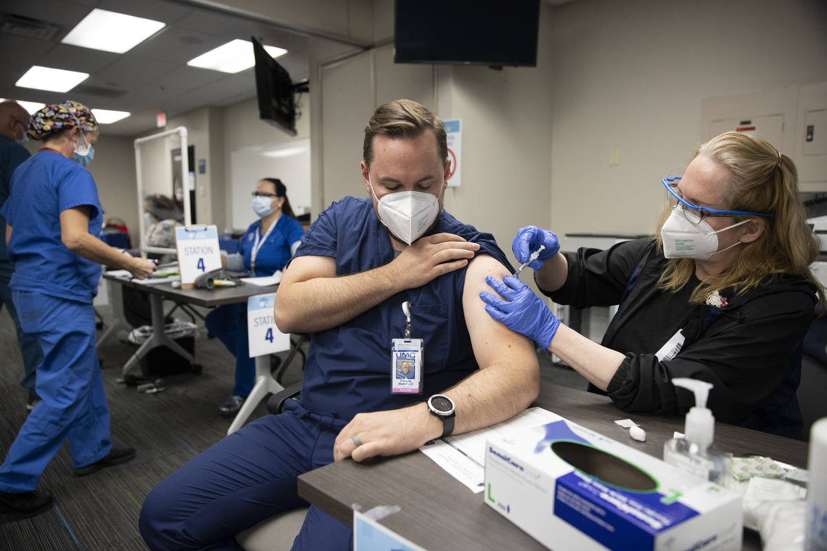 Dr. Rusty Walker, left, receives the second dose of the Pfizer COVID-19 vaccine from Registered ...