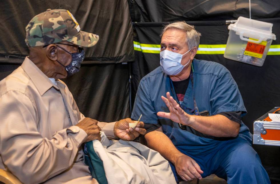 Veteran Mack A. McKinley receives shot follow-up information from RN Darrel Cowlishaw as some o ...