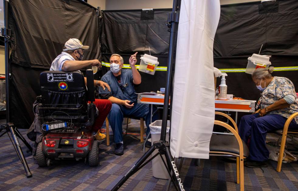 Veteran Levi Williams, left, receives shot follow-up information from RN Darrel Cowlishaw as so ...