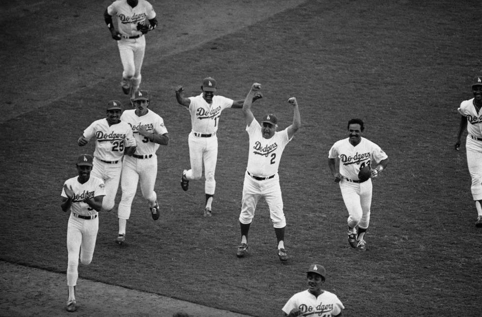 Los Angeles Dodgers manager Tommy Lasorda (2) and Rafael Landestoy (17) rush victoriously onto ...