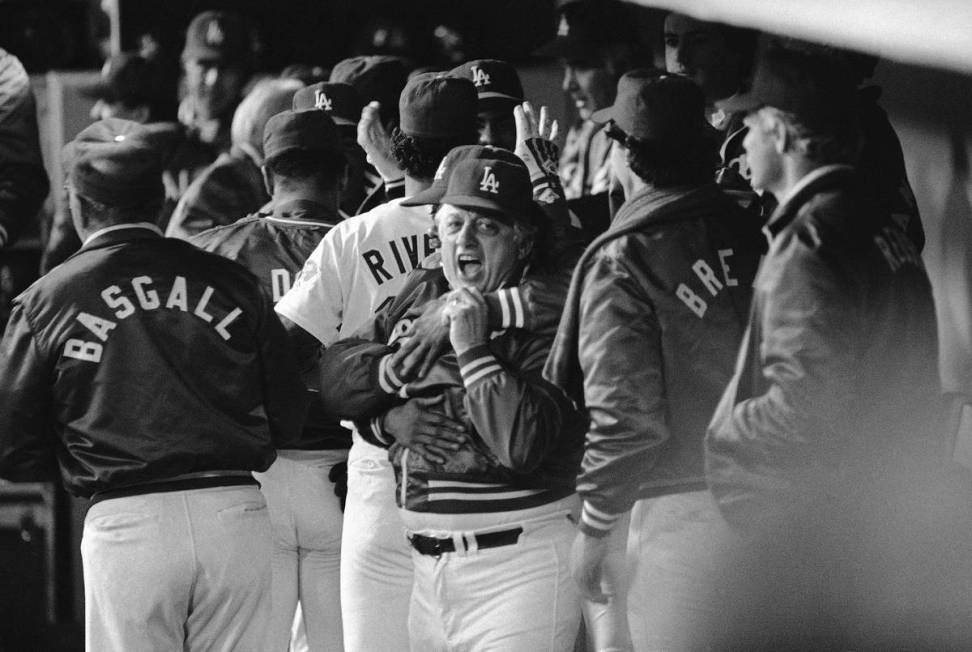 Los Angeles Dodgers manager Tommy Lasorda gets a winning hug from teammate Derrel Thomas, rear, ...