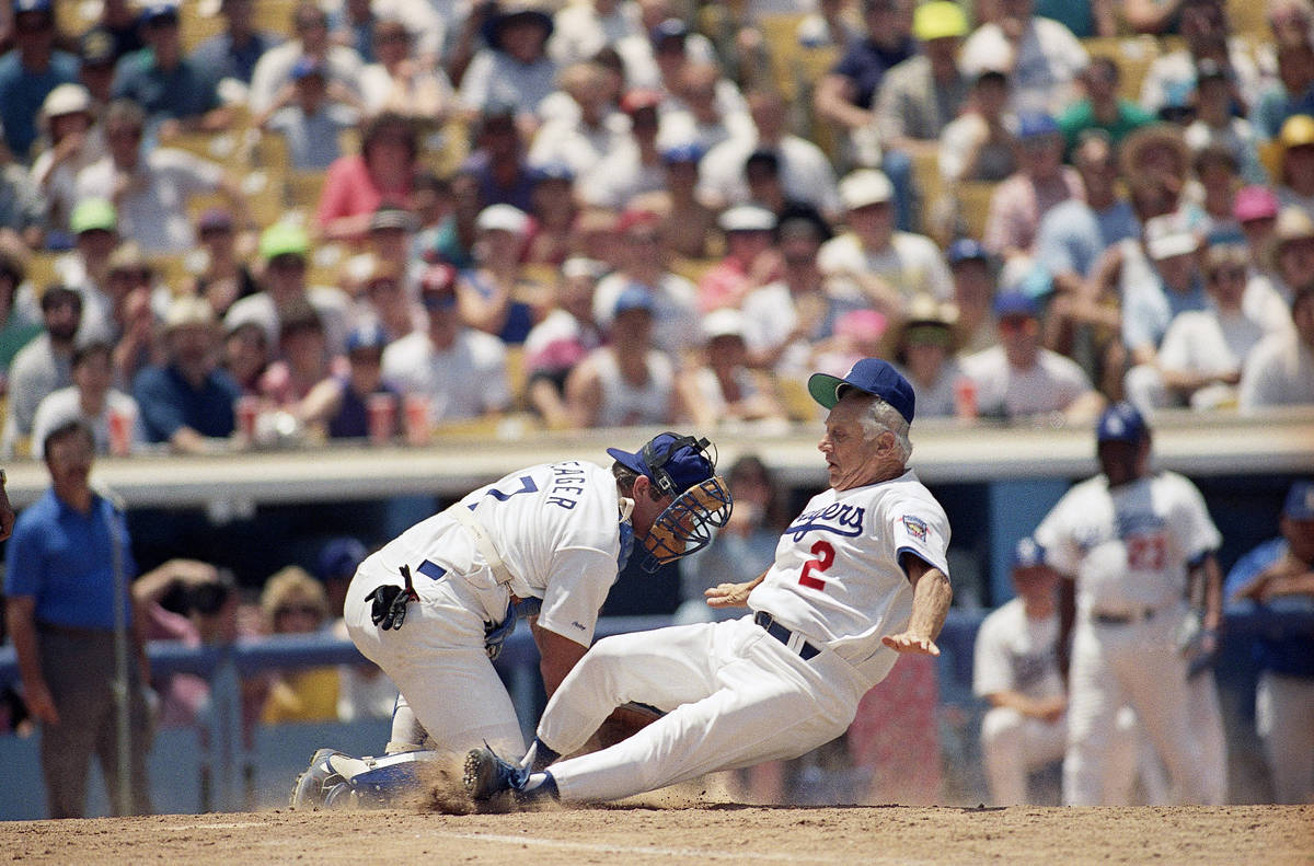 Los Angeles Dodgers manager Tommy Lasorda (2) slides safely home as catcher Steve Yeager fields ...
