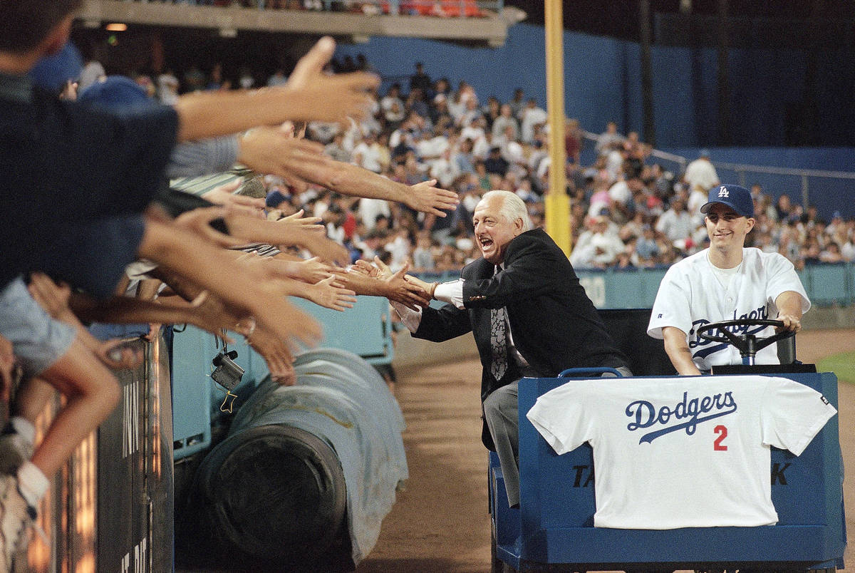 Former Los Angeles Dodgers manager Tommy Lasorda laughs as he reaches out for fans hands on Fri ...