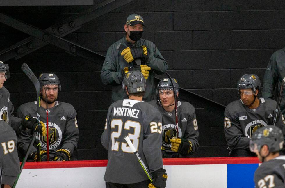 Golden Knights head coach Pete DeBoer, standing, looks on as Golden Knights defenseman Alec Mar ...