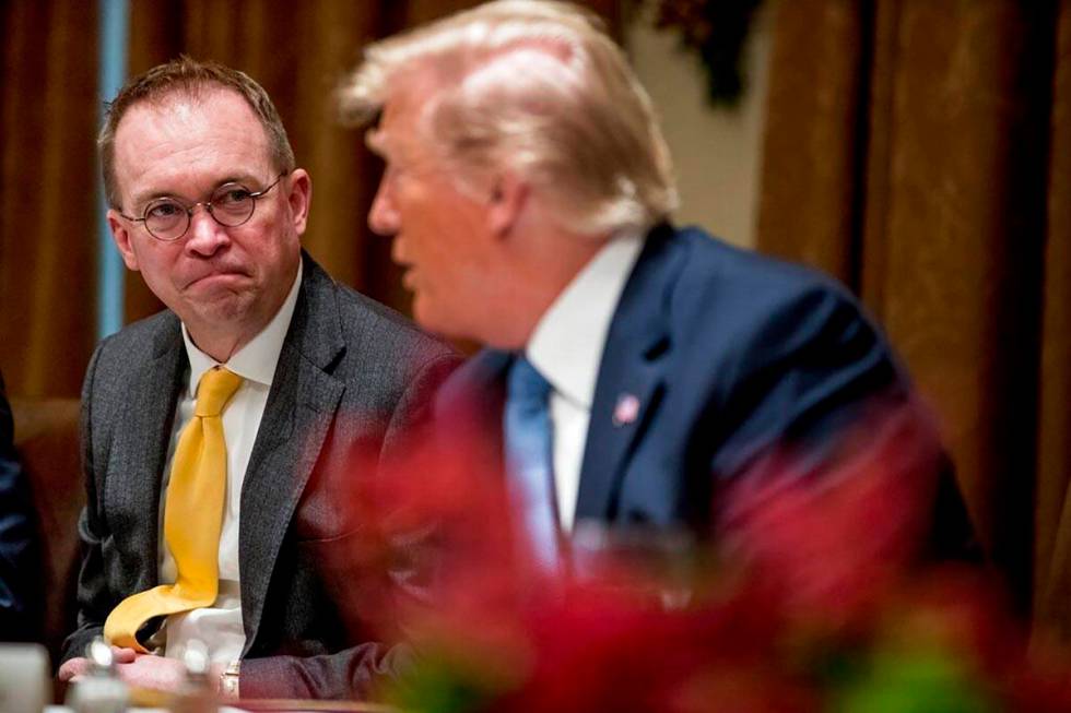In a Dec. 5, 2019, file photo, then-acting chief of staff Mick Mulvaney, left, listens to Presi ...