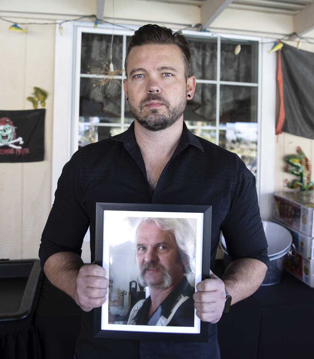Ethan Bondelid, 40, holds his slain father, Alan Bondelid, 70, photograph at his father's Las V ...