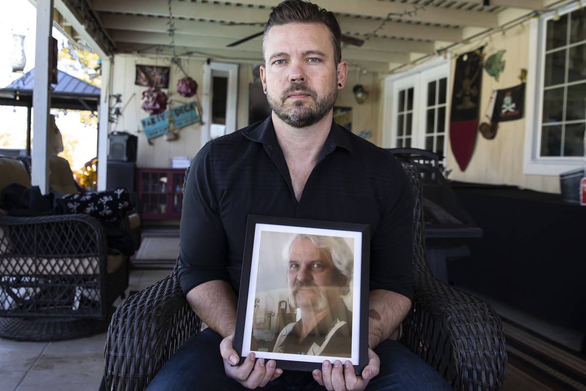 Ethan Bondelid, 40, holds a photograph of his slain father, Alan Bondelid, 70, at his father's ...