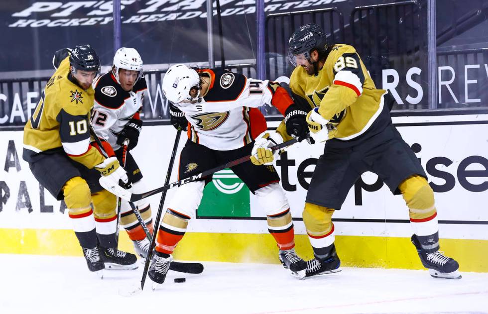 Golden Knights center Nicolas Roy (10) and right wing Alex Tuch (89) try to gain possession of ...