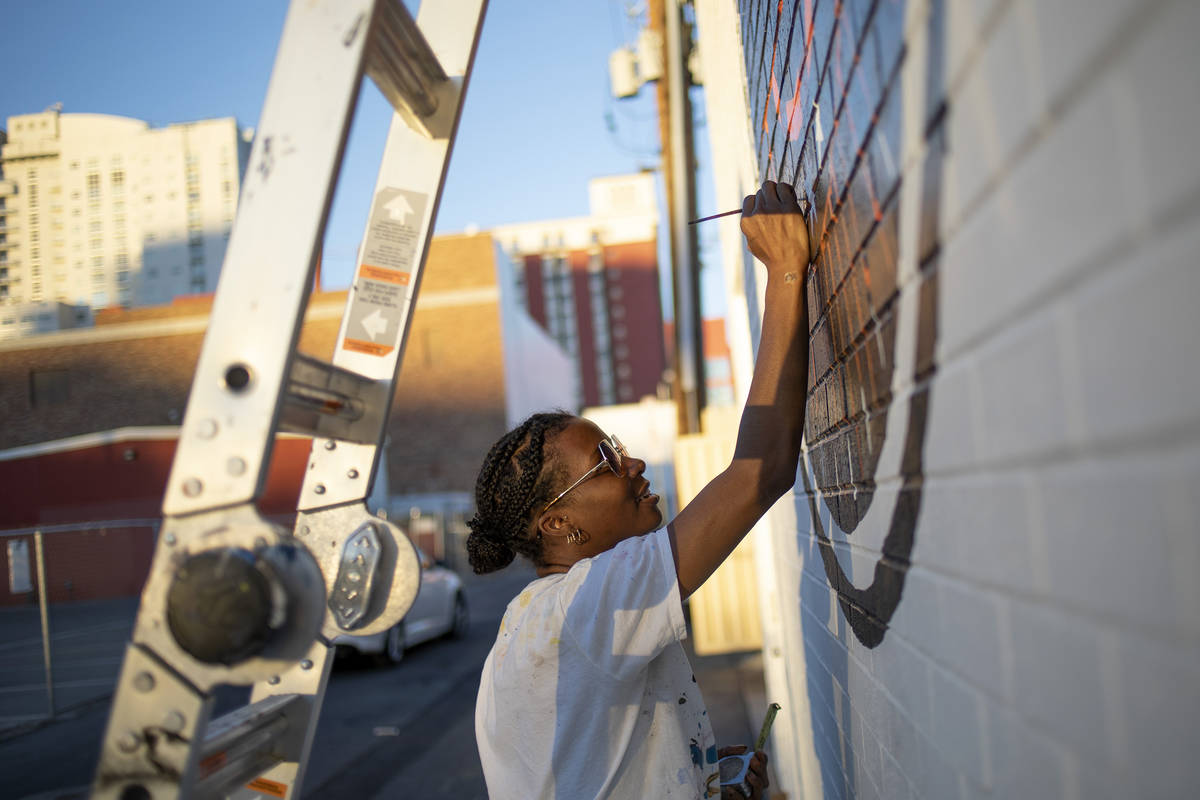 Krystal Rhema, an artist from Los Angeles, paints a mural on the exterior wall of a new, downto ...