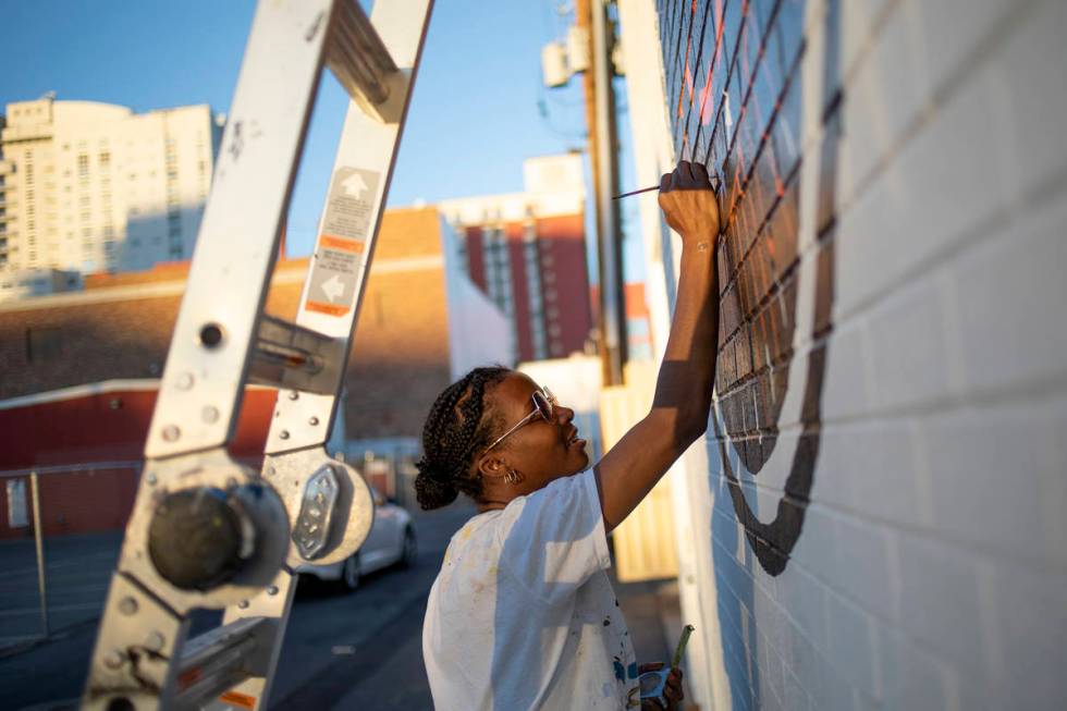 Krystal Rhema, an artist from Los Angeles, paints a mural on the exterior wall of a new, downto ...