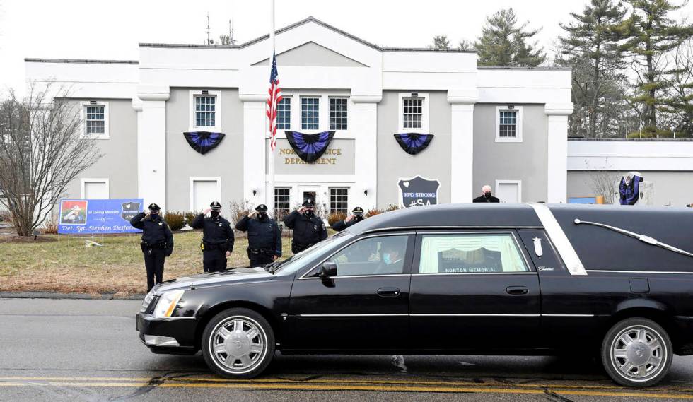 FILE - In this Thursday, Jan. 14, 2021. file photo, Norton, Mass. police salute as a hearse car ...