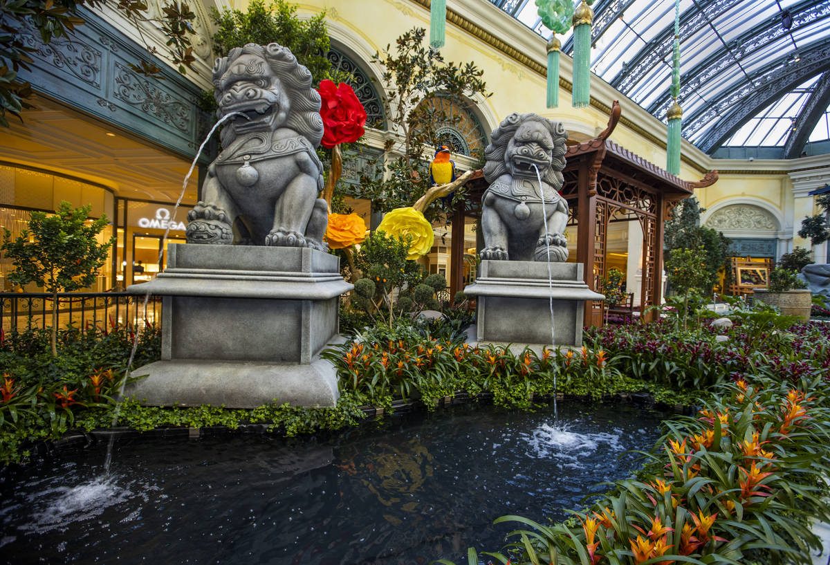 Statues with water coming out of their mouths are surrounded by a variety of flowers as the Bel ...