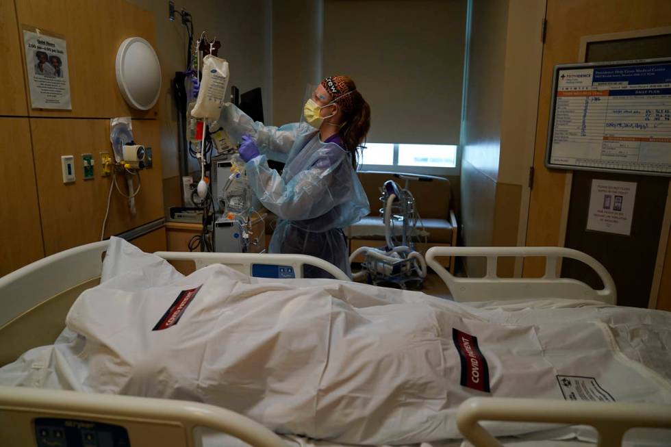 Registered nurse Nikki Hollinger cleans up a room as a body of a COVID-19 victim lies in a body ...