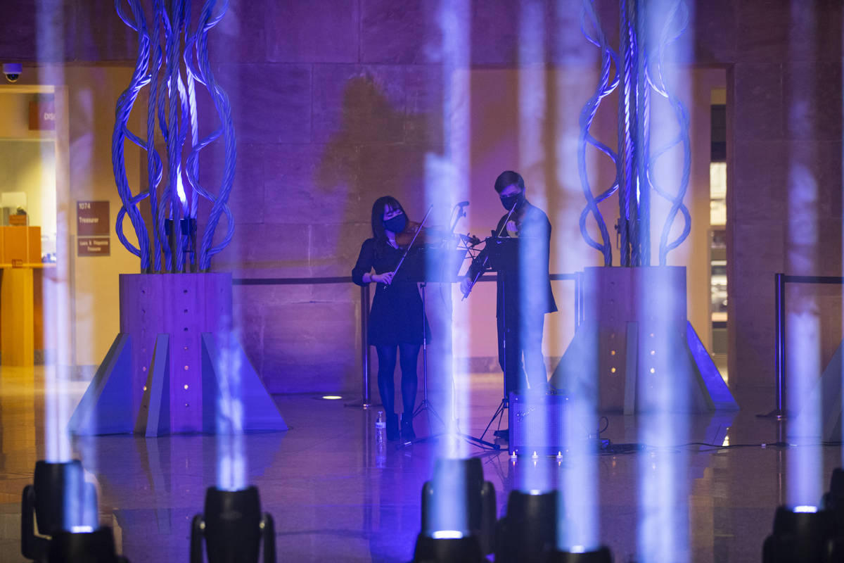 Violinists Wonyoung Na, left, and Dmytro Nehrych perform as 29 lights illuminate the rotunda at ...