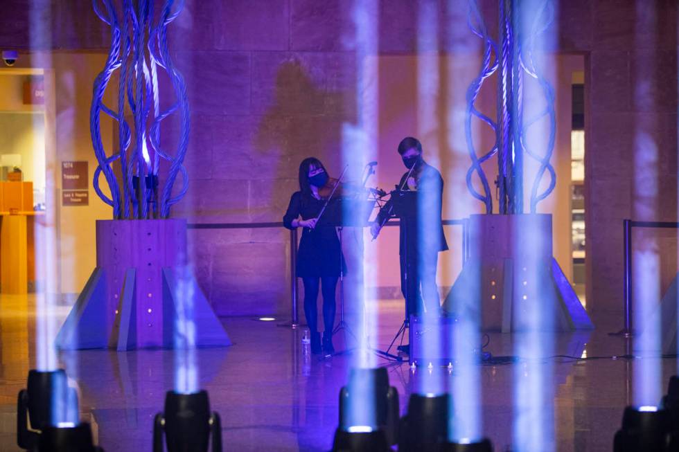 Violinists Wonyoung Na, left, and Dmytro Nehrych perform as 29 lights illuminate the rotunda at ...