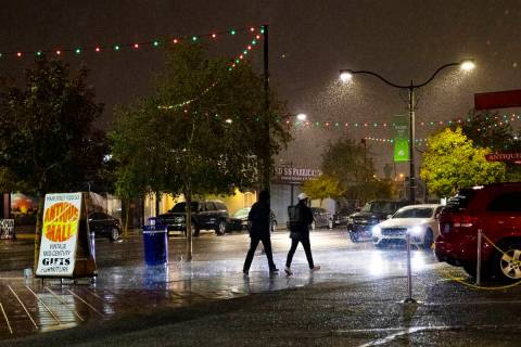 Pedestrians walk through the rain in the Arts District in Las Vegas on Dec. 17, 2020, the first ...
